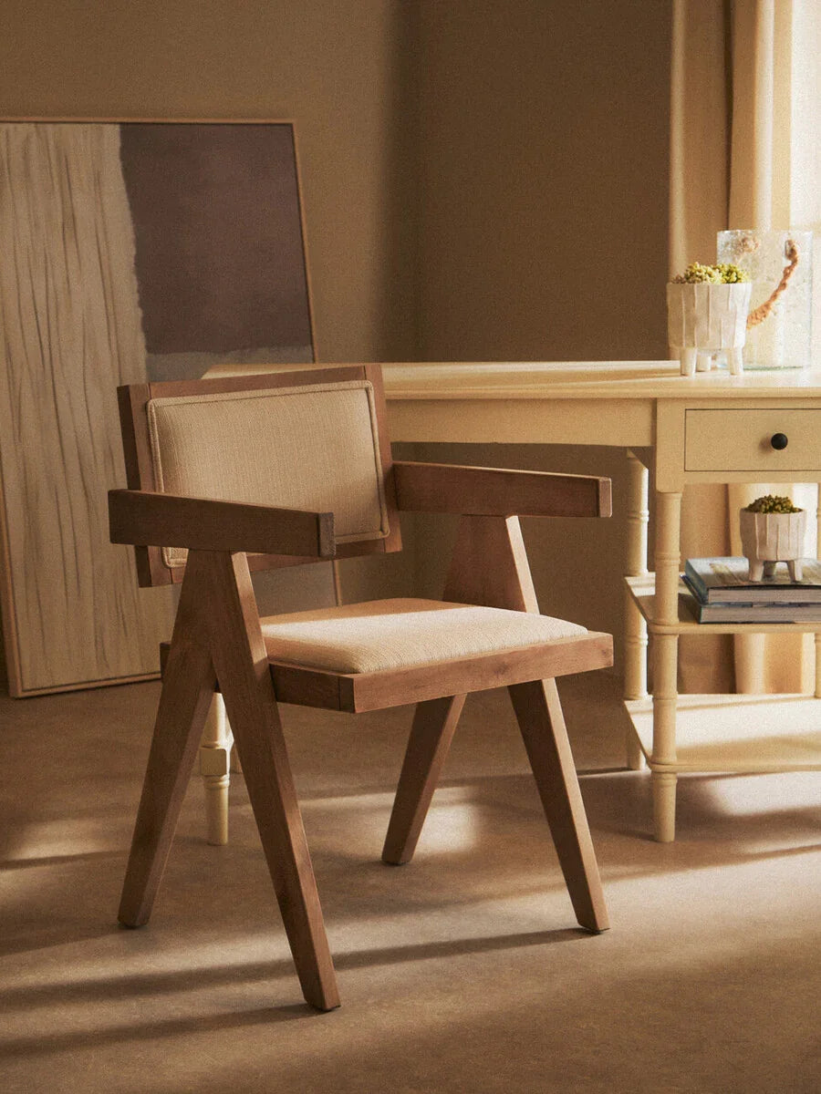 Wooden accent chair with beige cushioned seat and backrest beside light wood desk