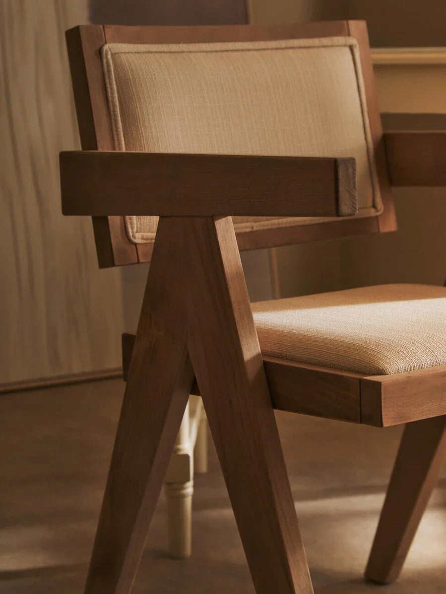 Modern wooden dining chair with beige cushioned seat and backrest, angled side view