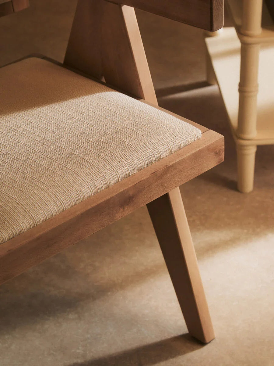 Close-up of wooden dining chair with light beige upholstered seat on tiled floor