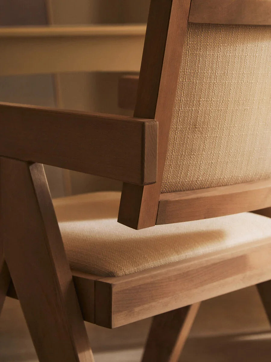 Wooden dining chair with light fabric seat and backrest, close-up side angle