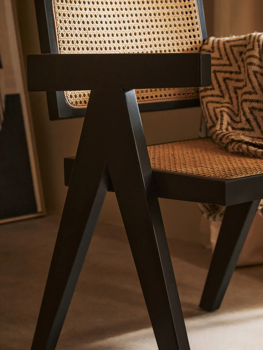 Modern rattan chair with black wood frame and woven cane seat in living room