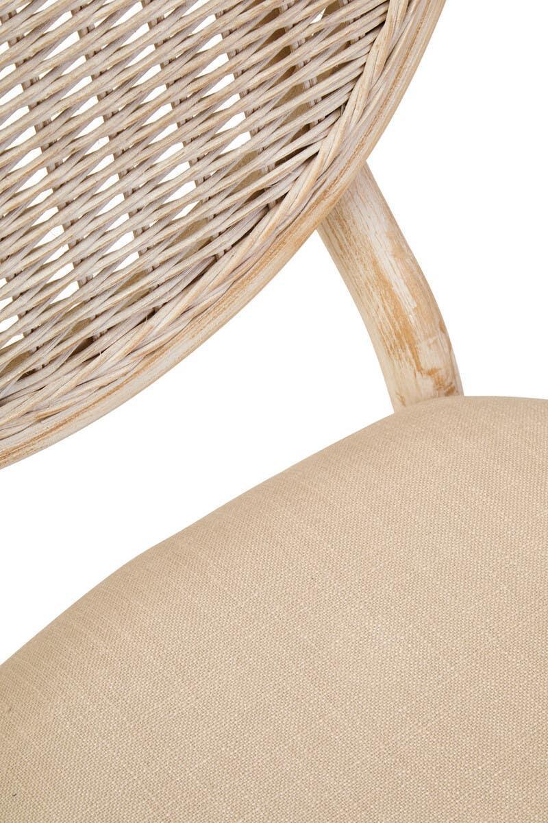 Close-up of rattan dining chair with beige fabric seat and curved wooden backrest