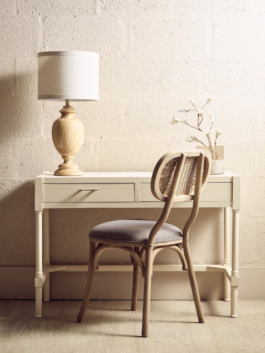 Cream wooden dressing table set with rattan chair, table lamp, and minimalist decor