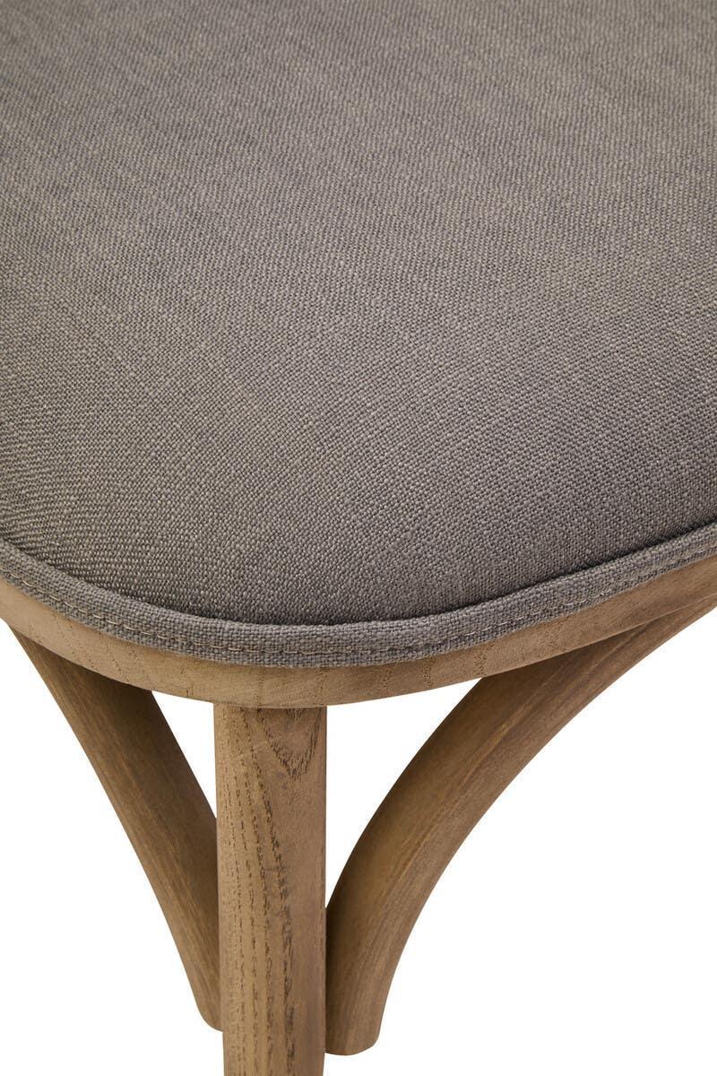 Close view of grey upholstered dining chair seat with light wood frame and curved legs
