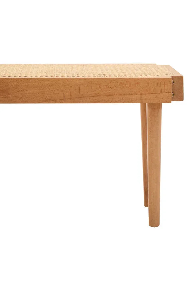 Wooden bench with woven rattan seat and two tapered legs, side view