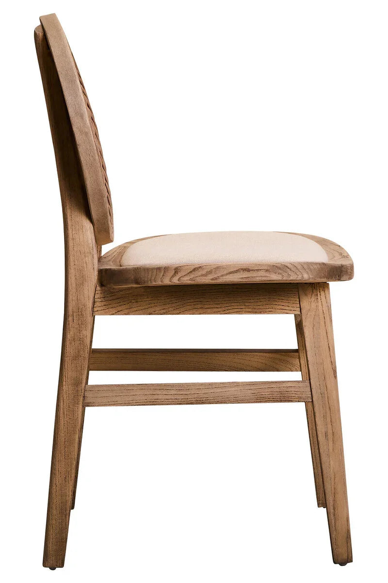 Side view of wooden dining chair with beige fabric seat and carved backrest