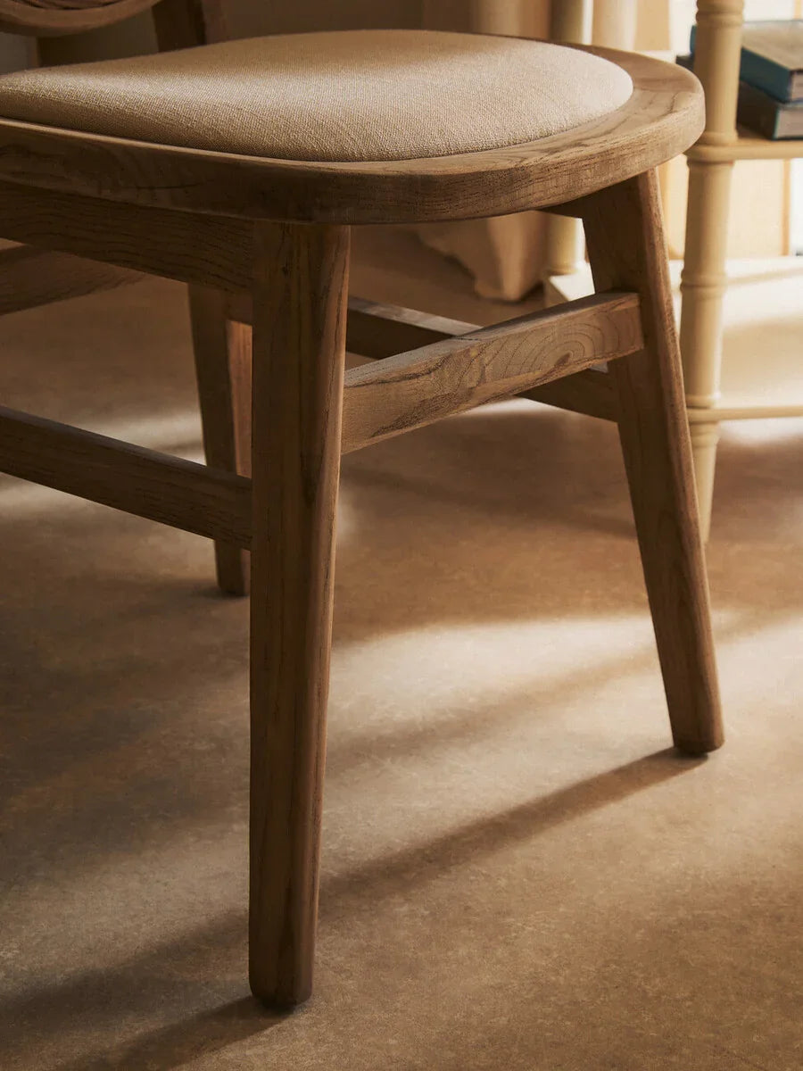Oak dining chair with light fabric seat cushion, angled side view on wooden floor