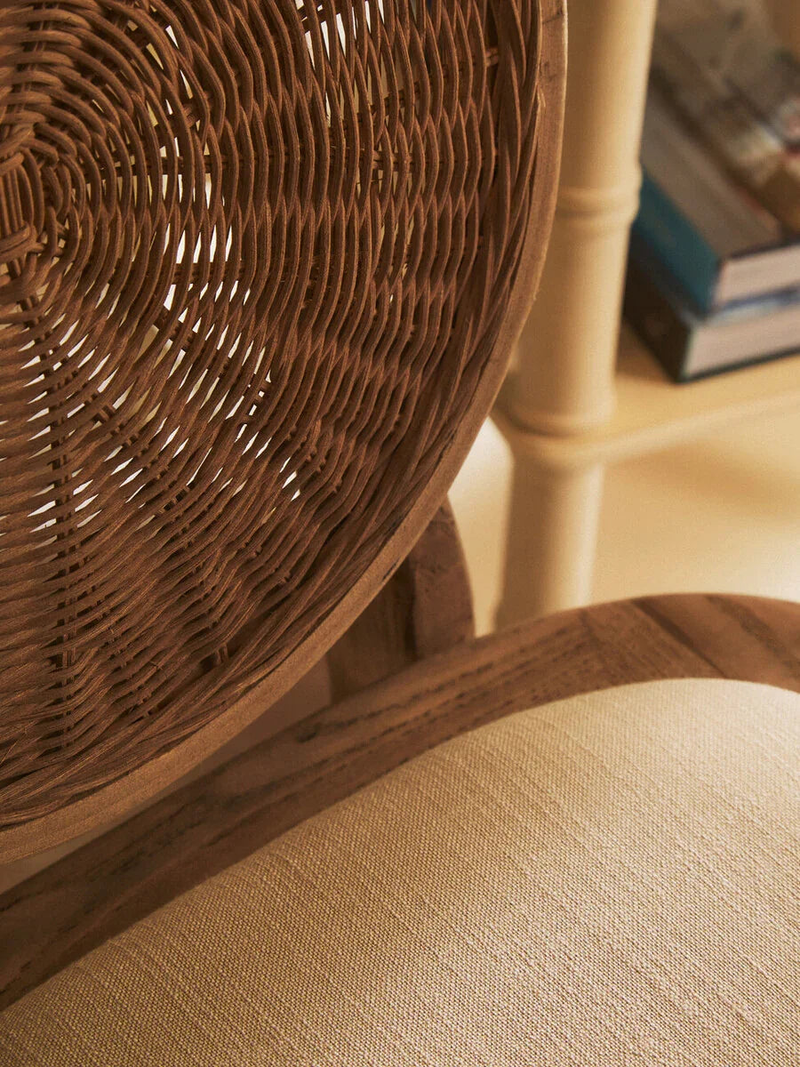 Closeup of rattan dining chair backrest and beige fabric seat cushion
