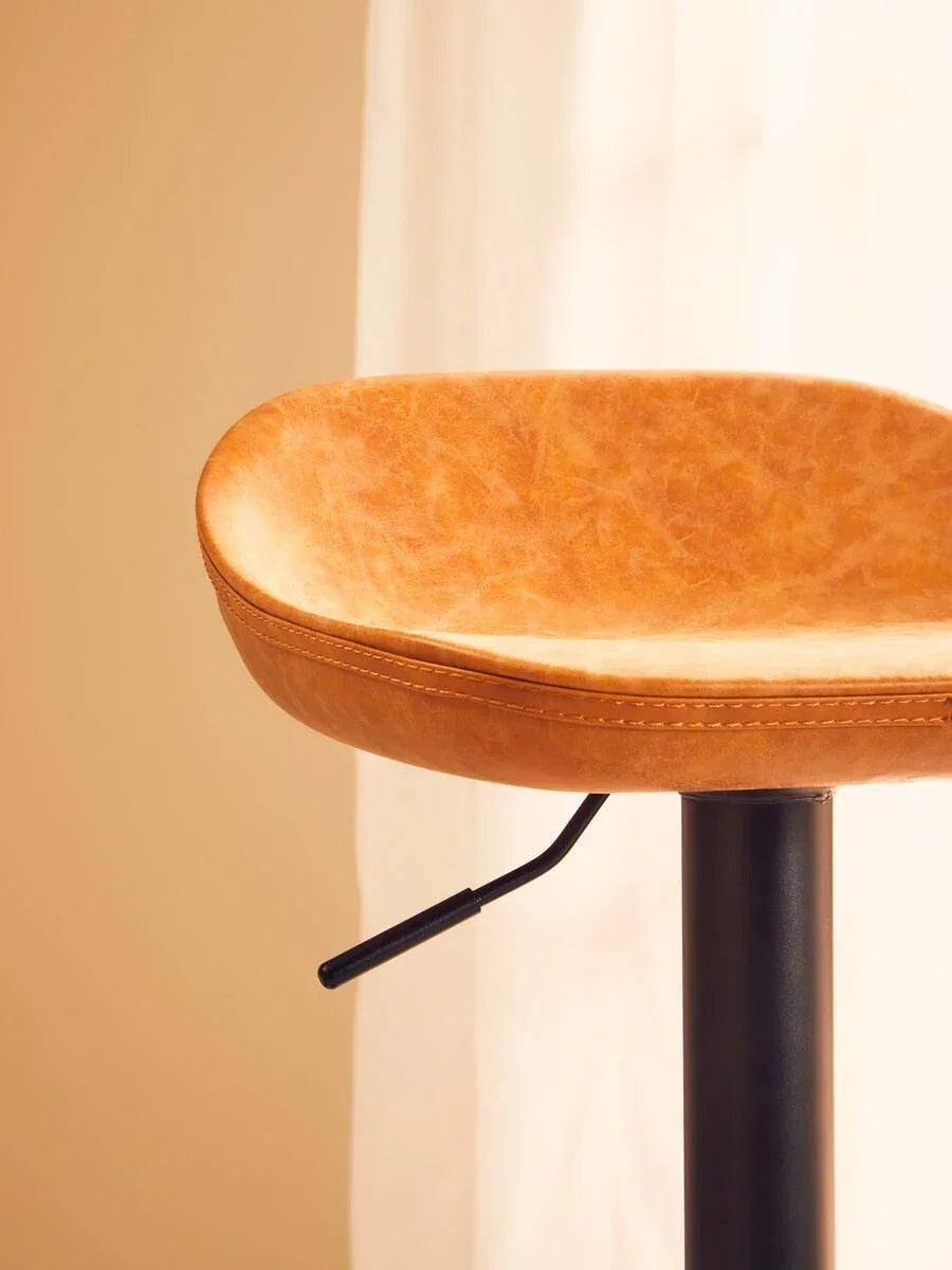 Tan leather bar stool seat with black metal base and adjustable lever, side view