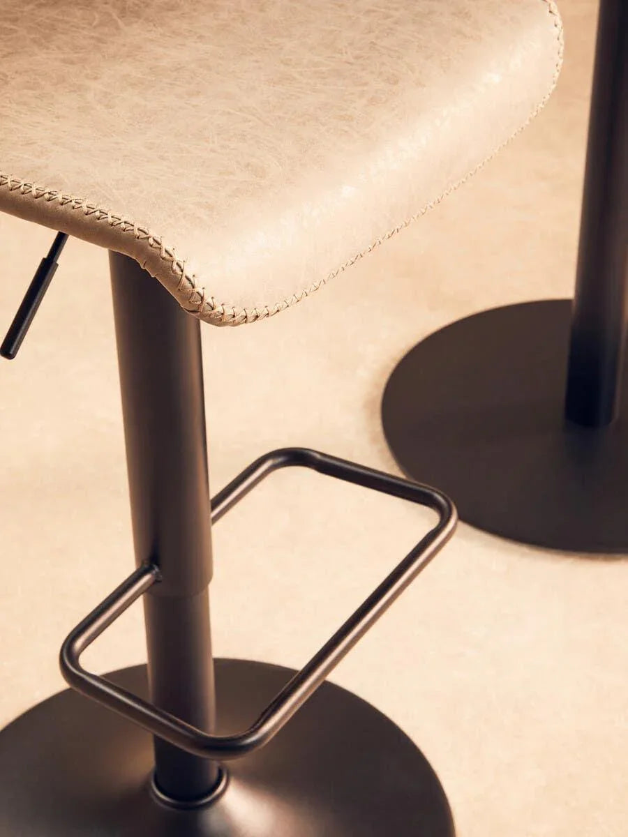 Close-up of beige faux leather bar stool with black metal base and footrest