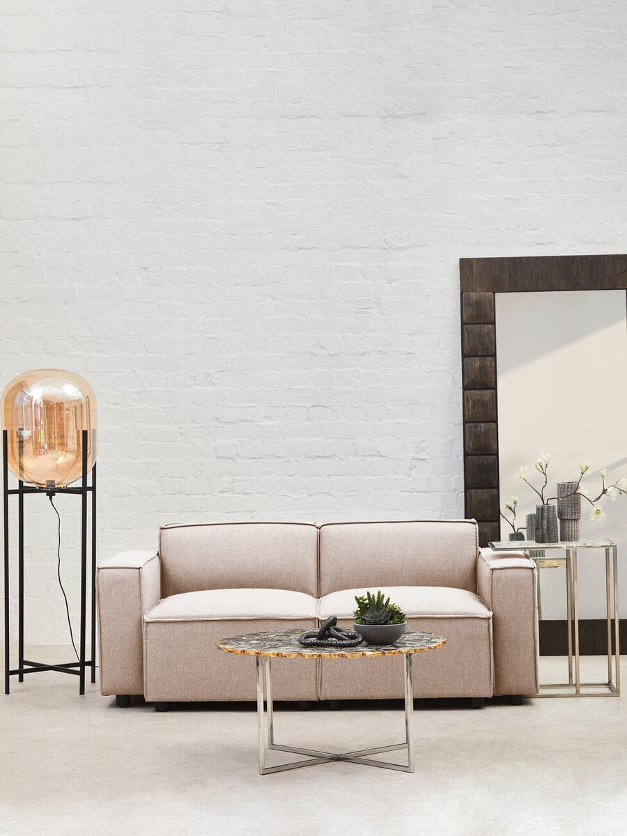 Armless modular sofa in natural fabric, featuring a minimalist design with soft cushions, placed in a bright room with a large mirror and a small coffee table holding a decorative plant