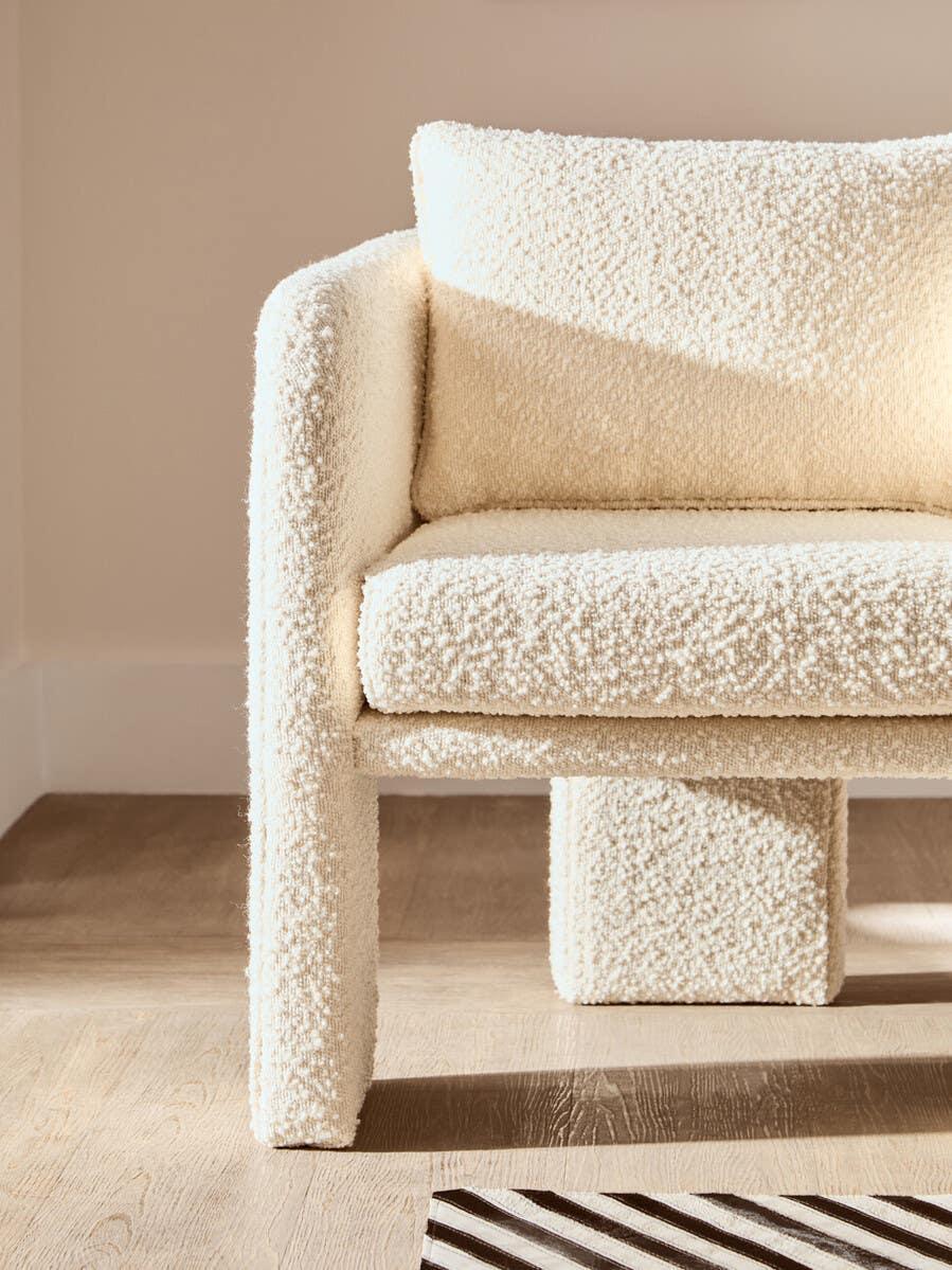 Cream boucle armchair with square cushion and modern design on light wood floor