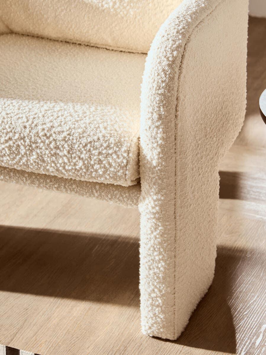 Cream boucle armchair corner with curved armrest on light wood floor