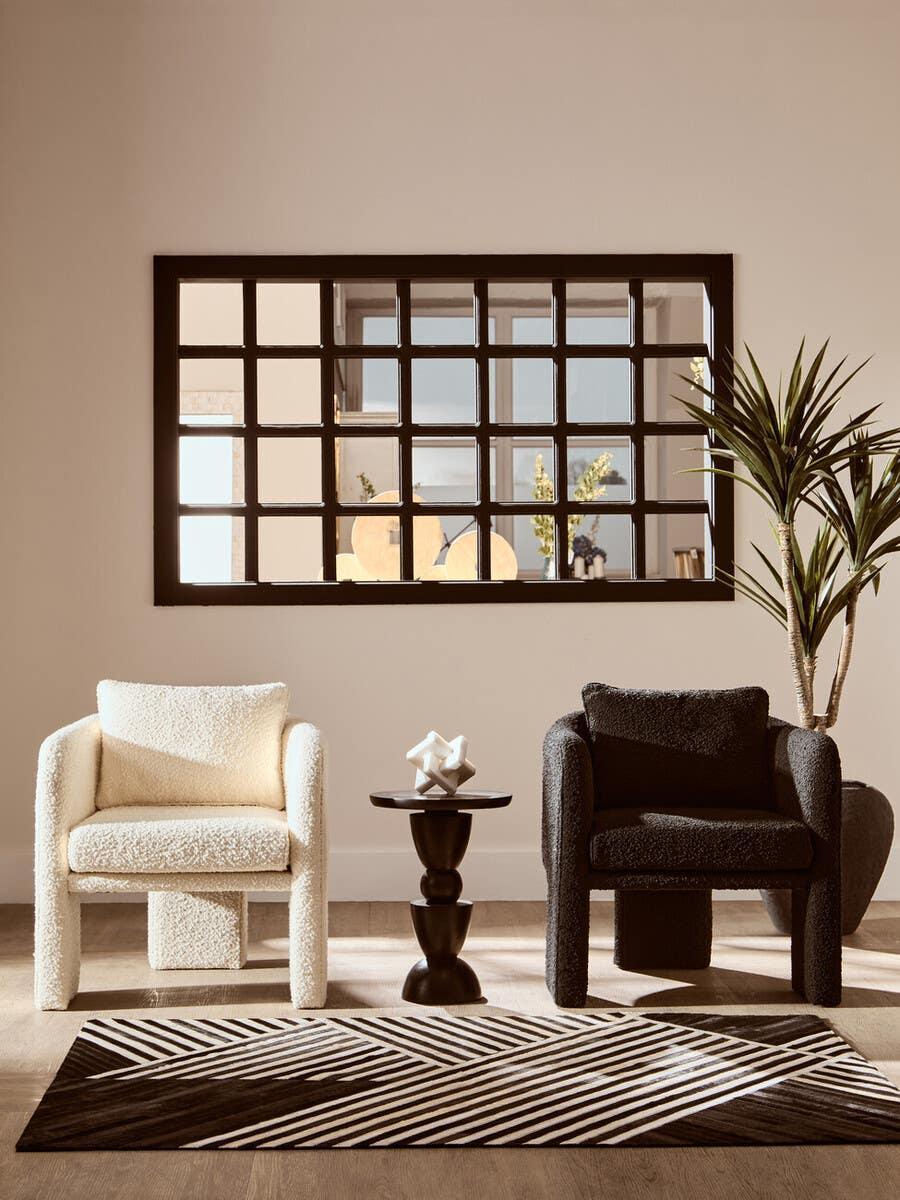 Black and cream boucle armchairs with accent table and geometric rug in modern living room