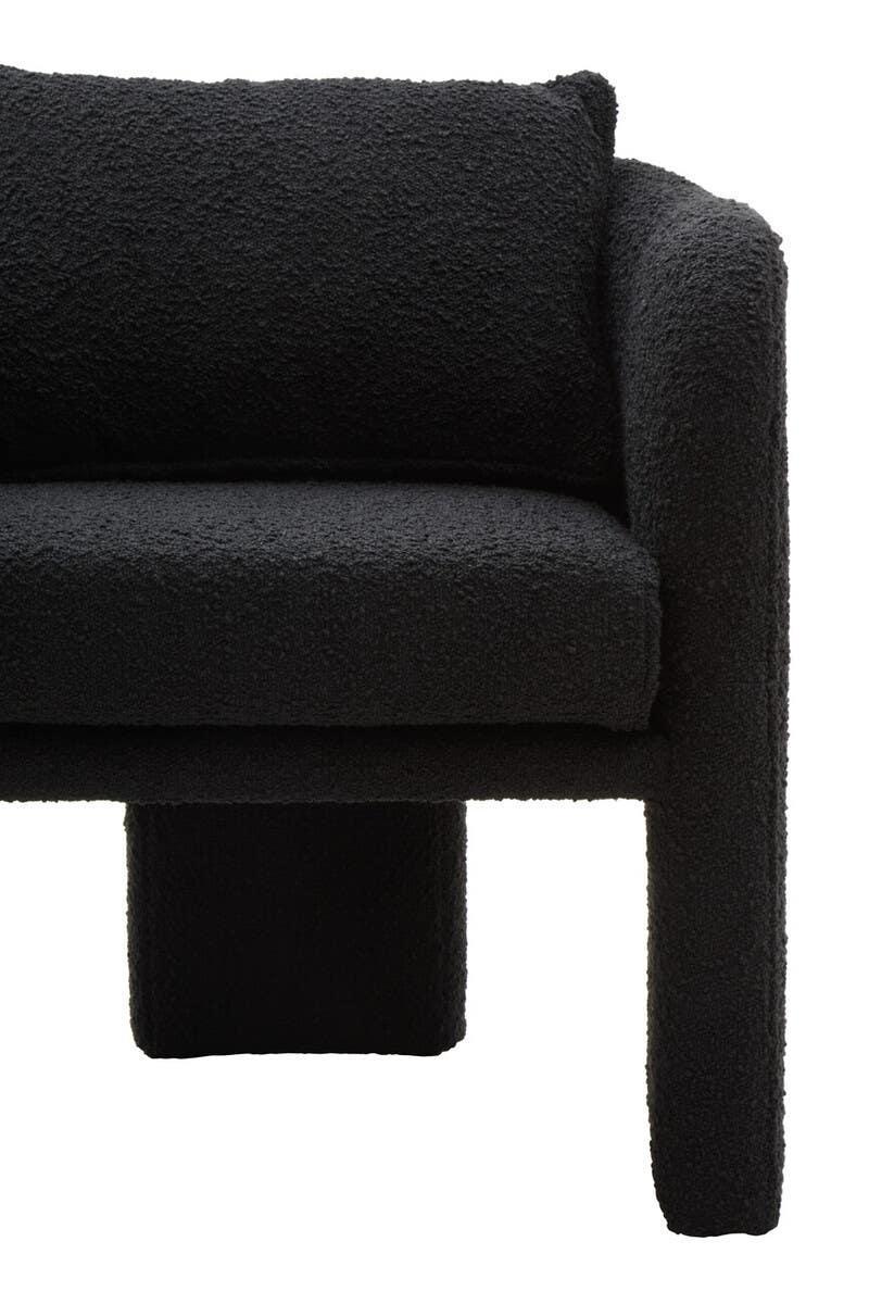 Close-up of black boucle fabric sofa with curved armrest and cushion detail