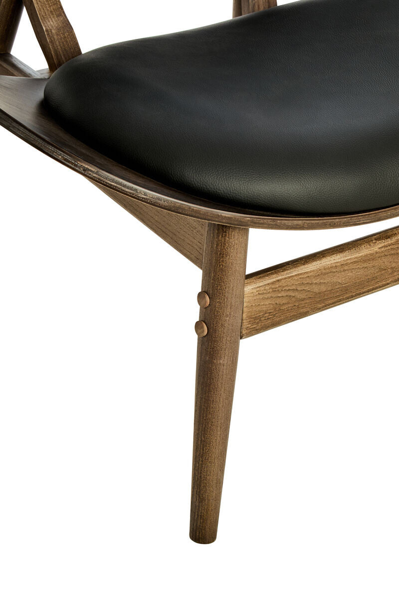 Black leather effect seat cushion with a smooth finish, supported by a sturdy elm wood frame featuring tapered legs and decorative wooden buttons.