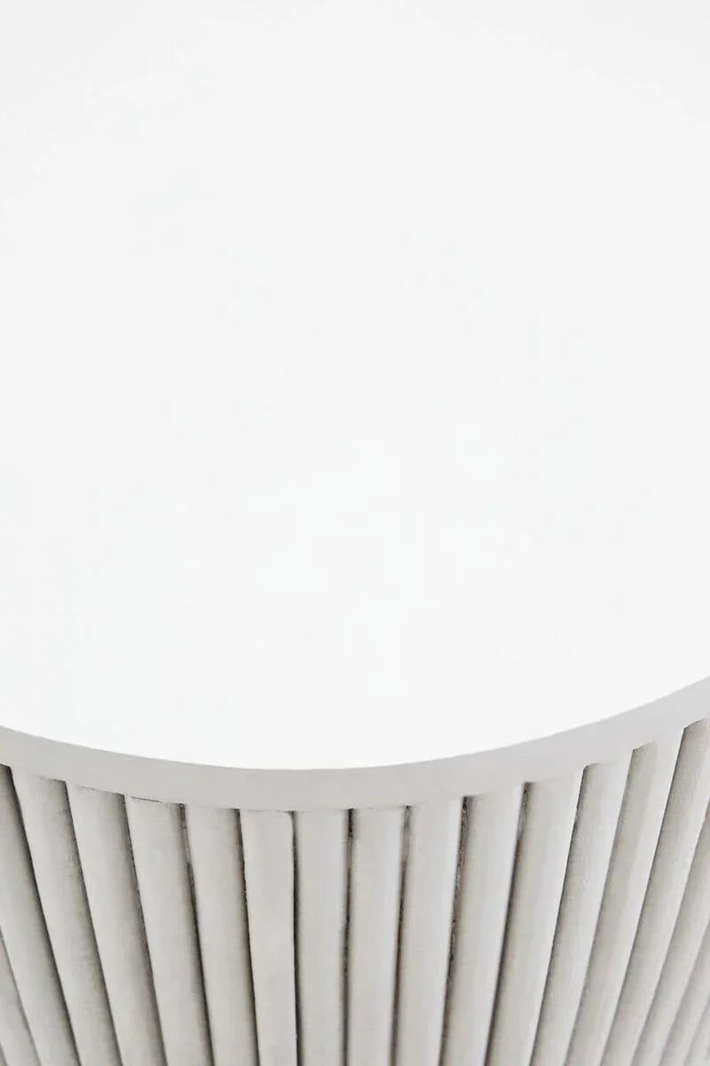 Round white coffee table with vertical slat details on the base, close view