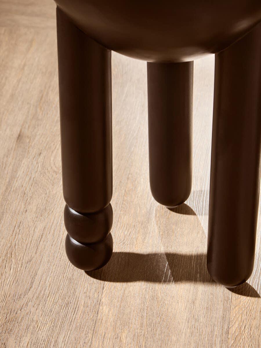 Brown wooden stool legs with rounded detailing on light wood floor