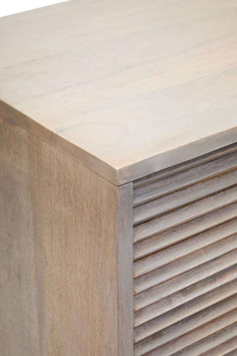 Light wood cabinet corner with slatted door detail and smooth top surface