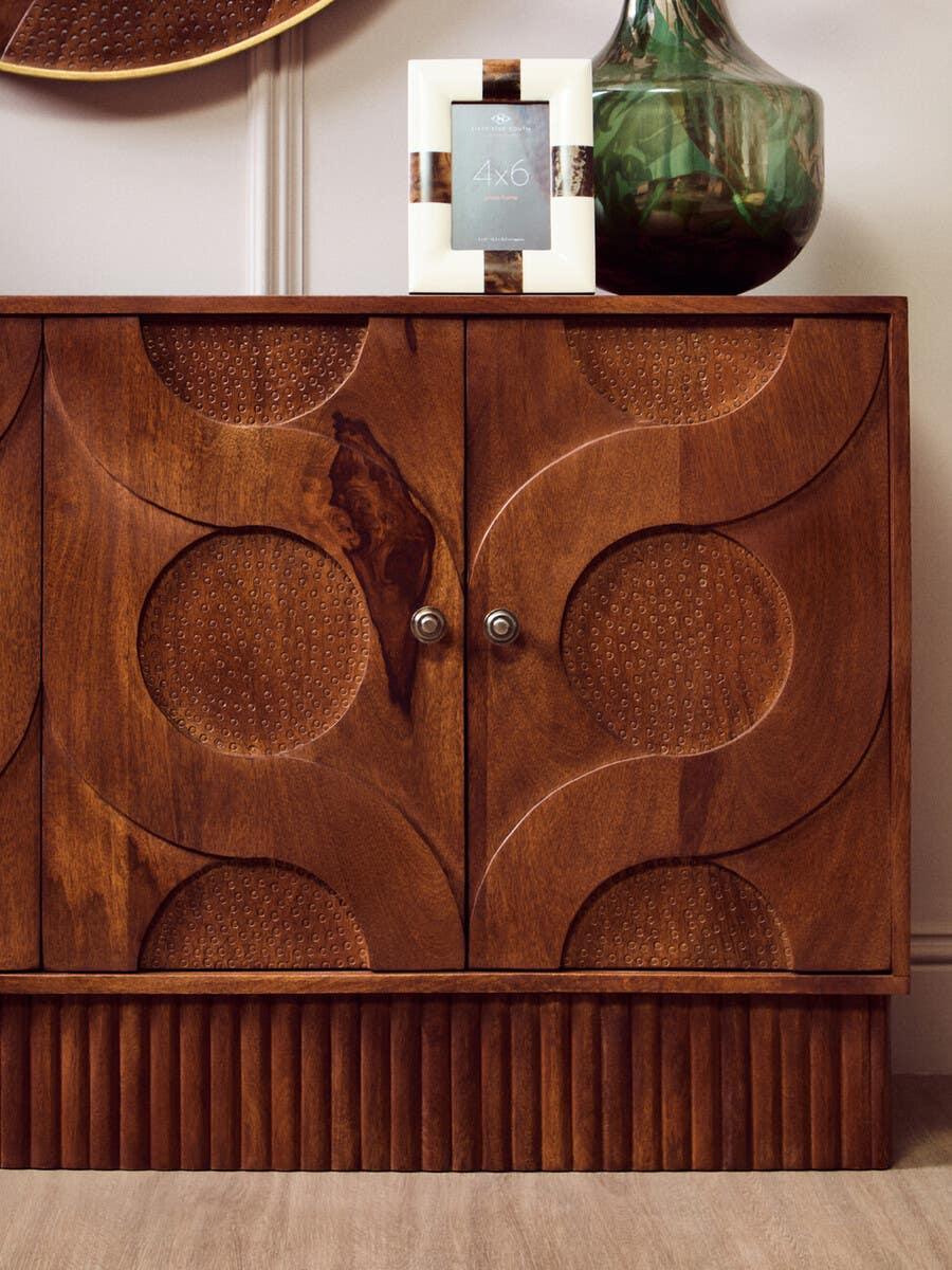 Carved wood sideboard with geometric circle patterns, fluted base, and double doors