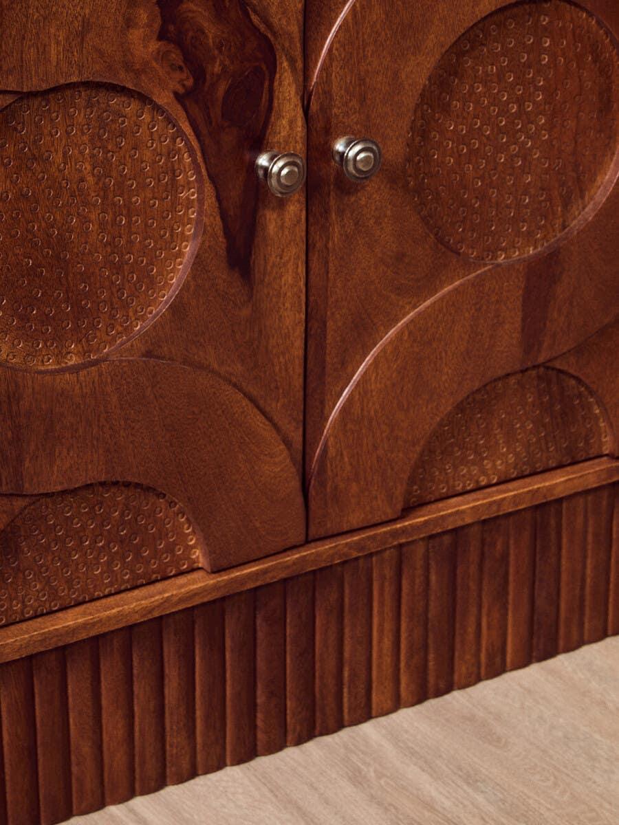 Wooden cabinet with textured geometric patterns and metal knobs on doors
