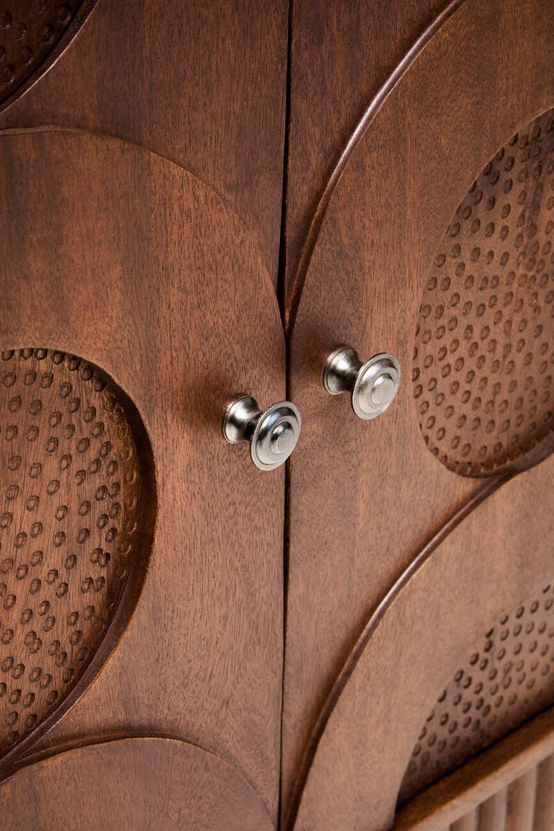 Close view of wooden cabinet doors with carved geometric pattern and metal handles