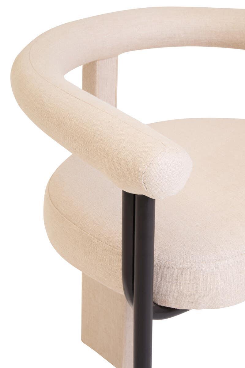 Beige fabric accent chair with curved backrest and black metal frame, close-up view