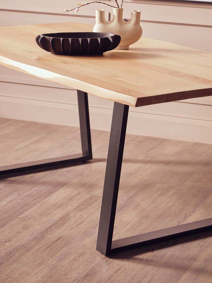 Rectangular wooden dining table with black metal legs, decorative bowl and vase on top