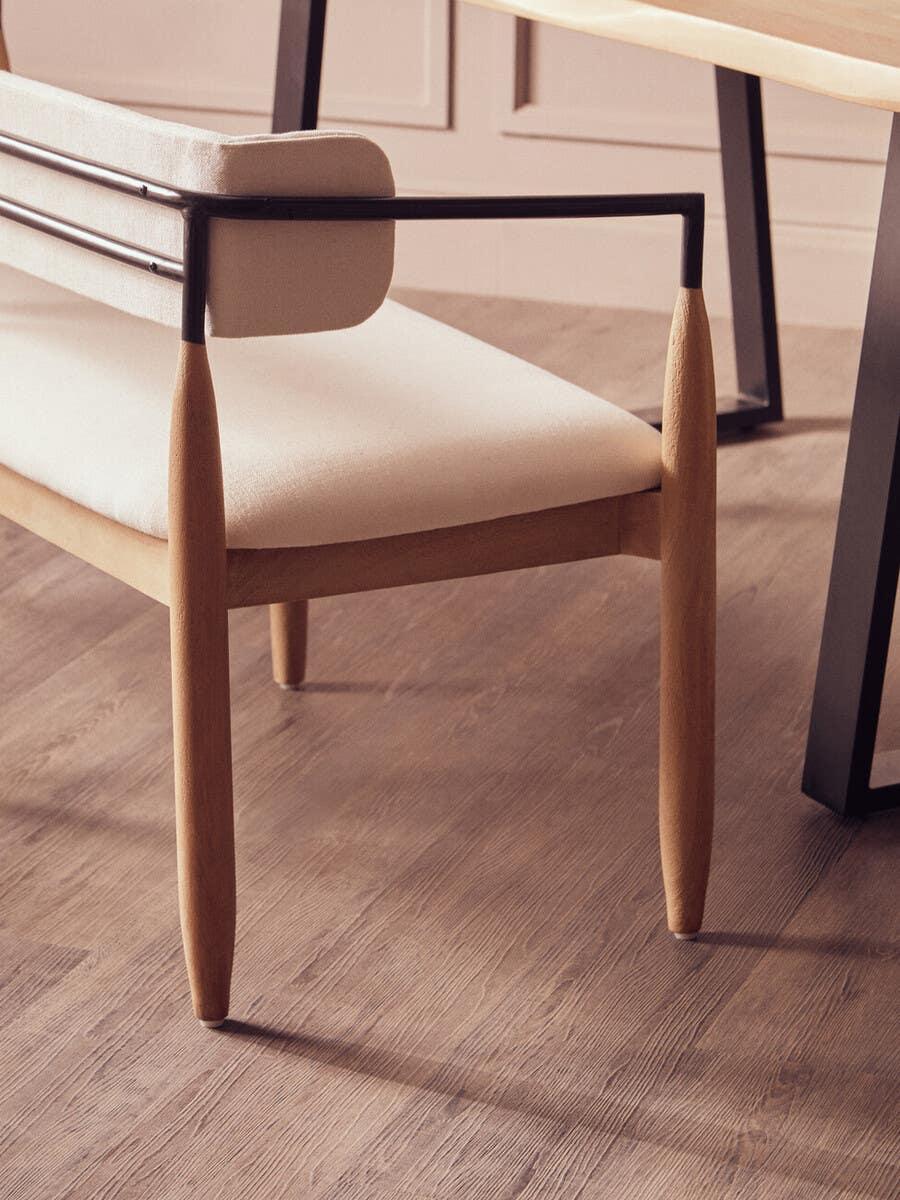 Modern dining chair with light wood frame, cream upholstery and black metal armrests