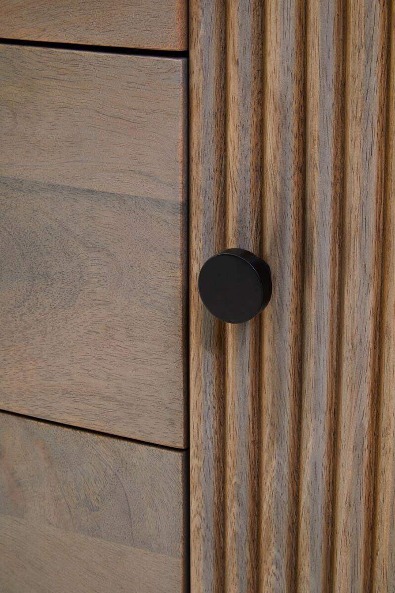 Walnut wood cabinet drawer with fluted detail and black round metal handle close up