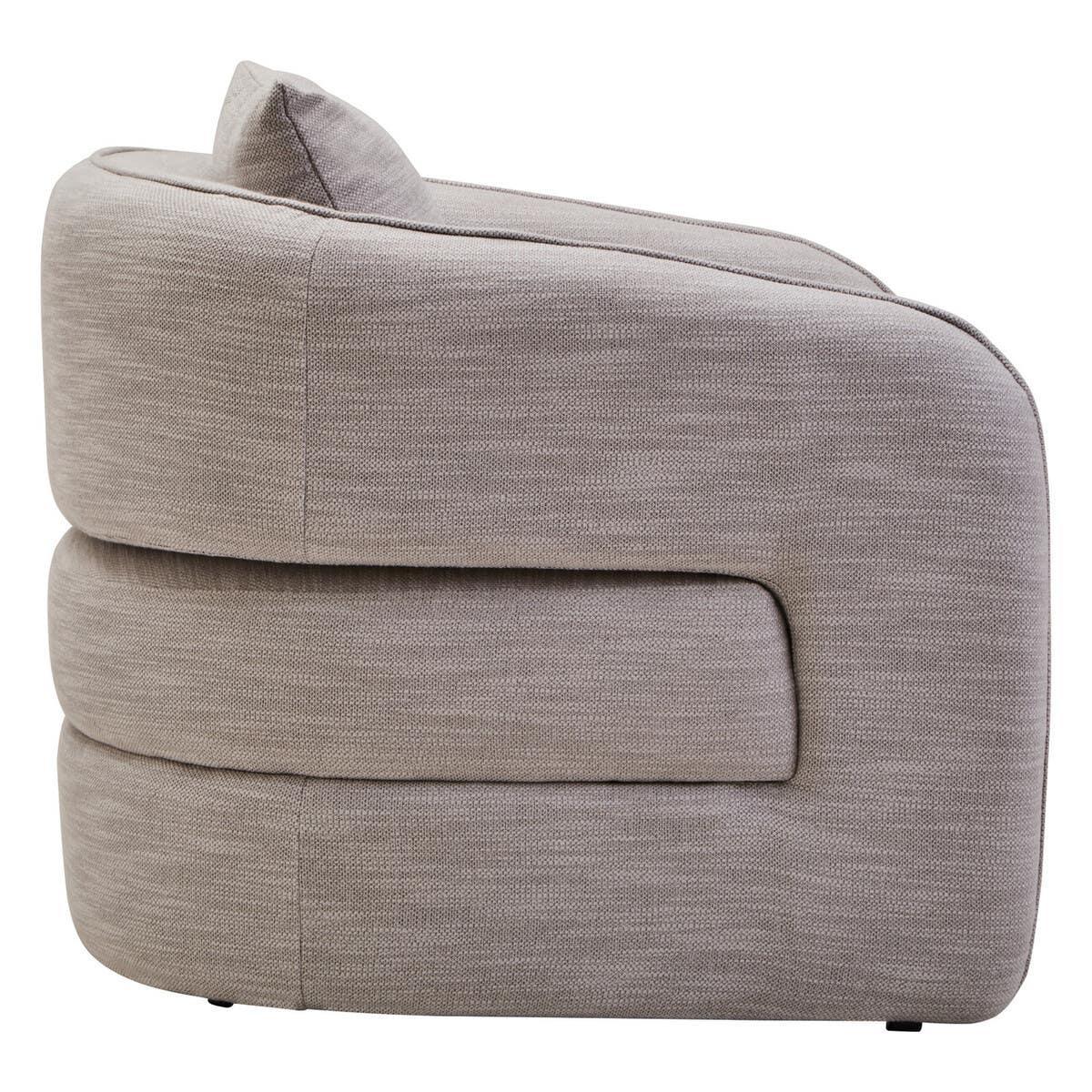 Side view of modern beige fabric sofa with curved armrest and plush cushion