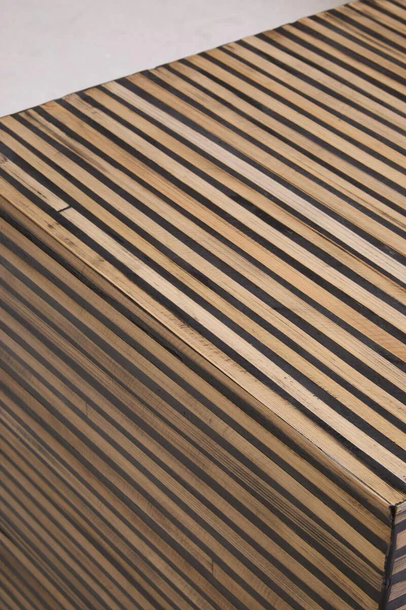 Striped wood storage chest corner showing black and natural grain detail