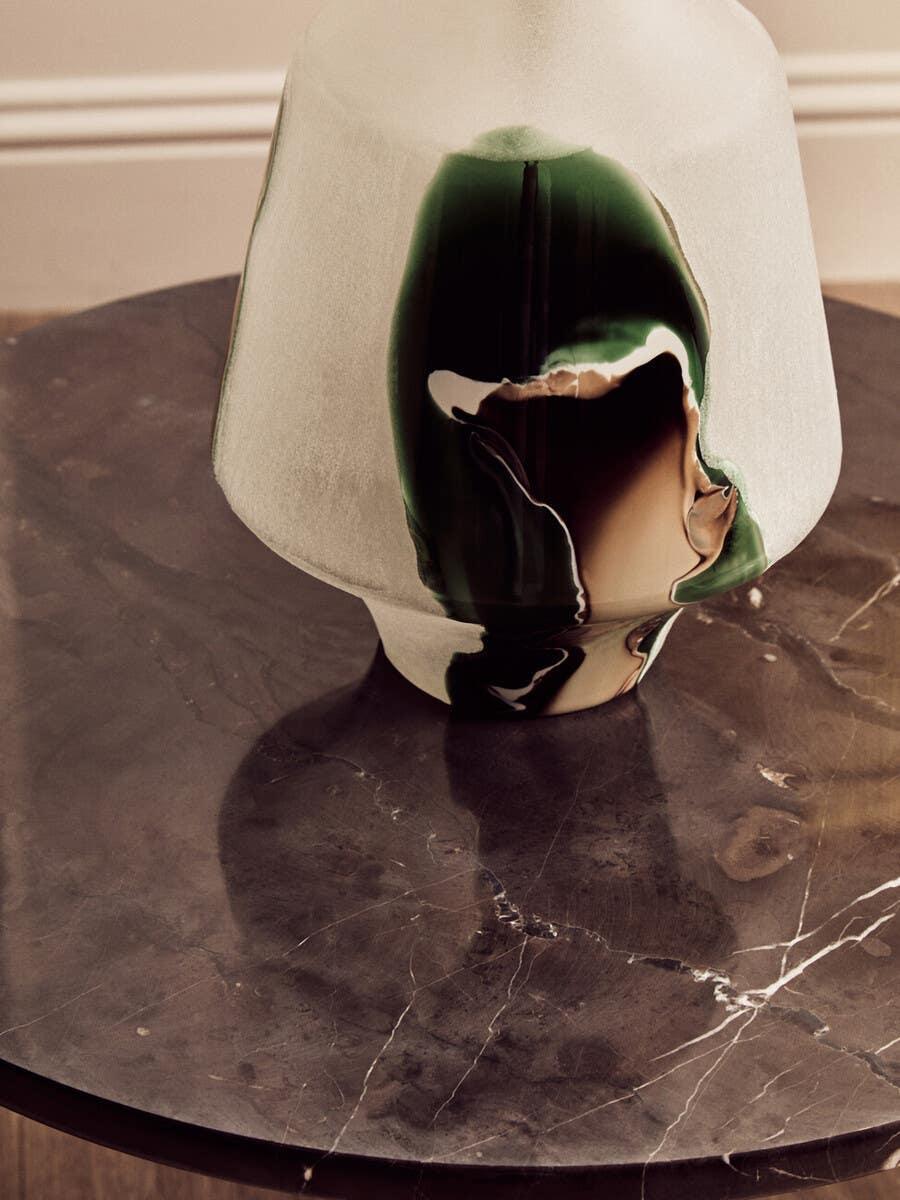 Abstract glass vase with green and brown detail on round dark marble coffee table