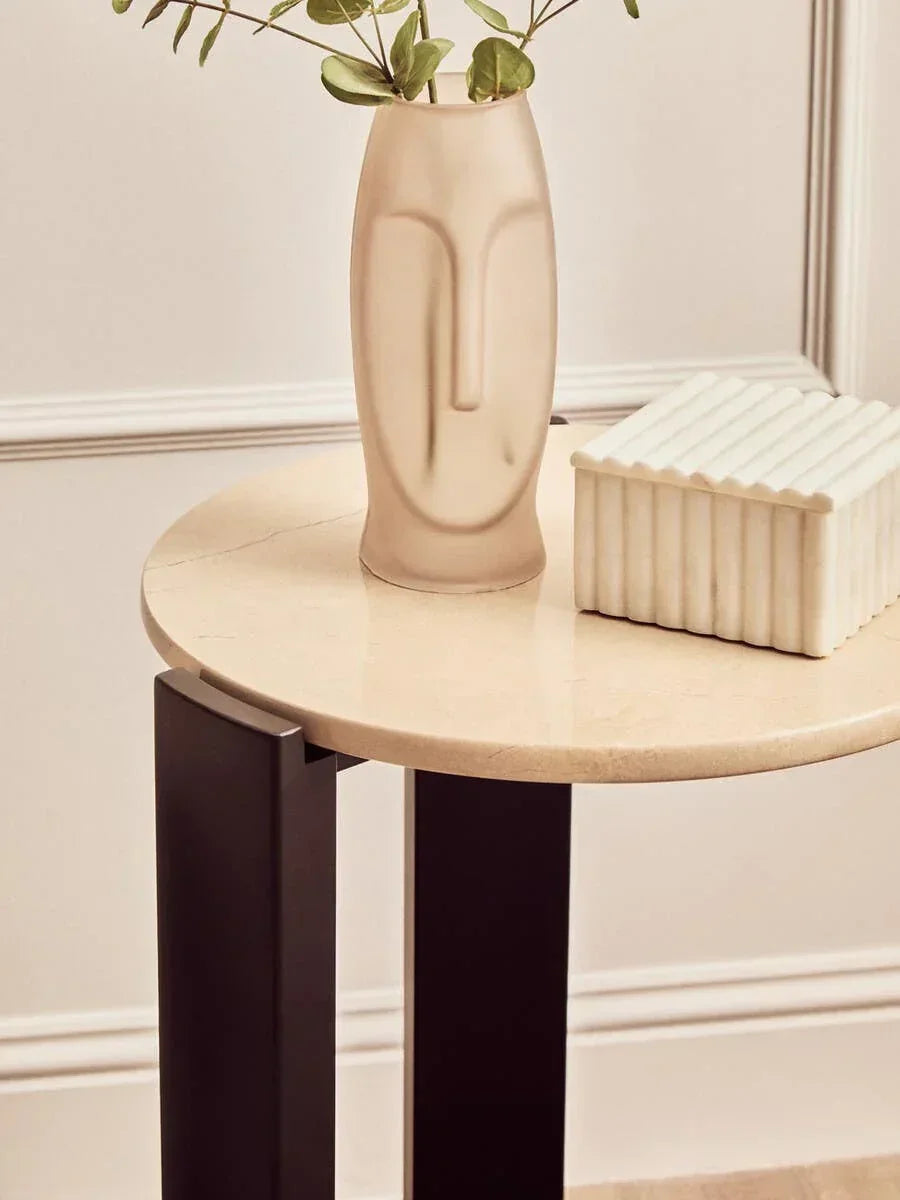 round marble side table with black legs styled with ceramic vase and decorative box