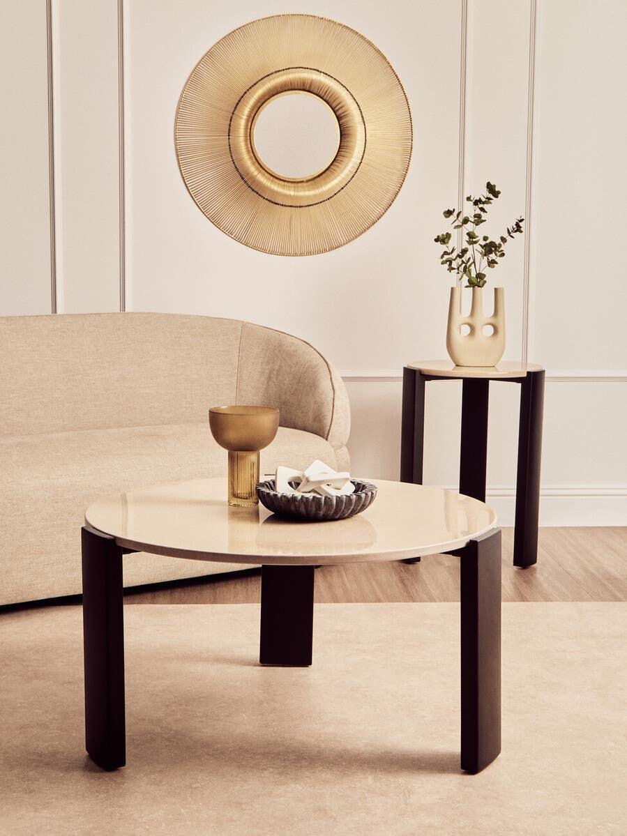 Modern beige sofa with round coffee table and side table in a neutral living room setting