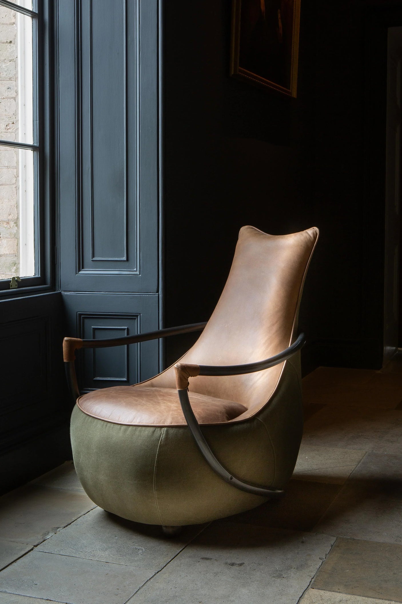 Modern accent armchair with tan leather seat, metal frame, and olive green fabric base