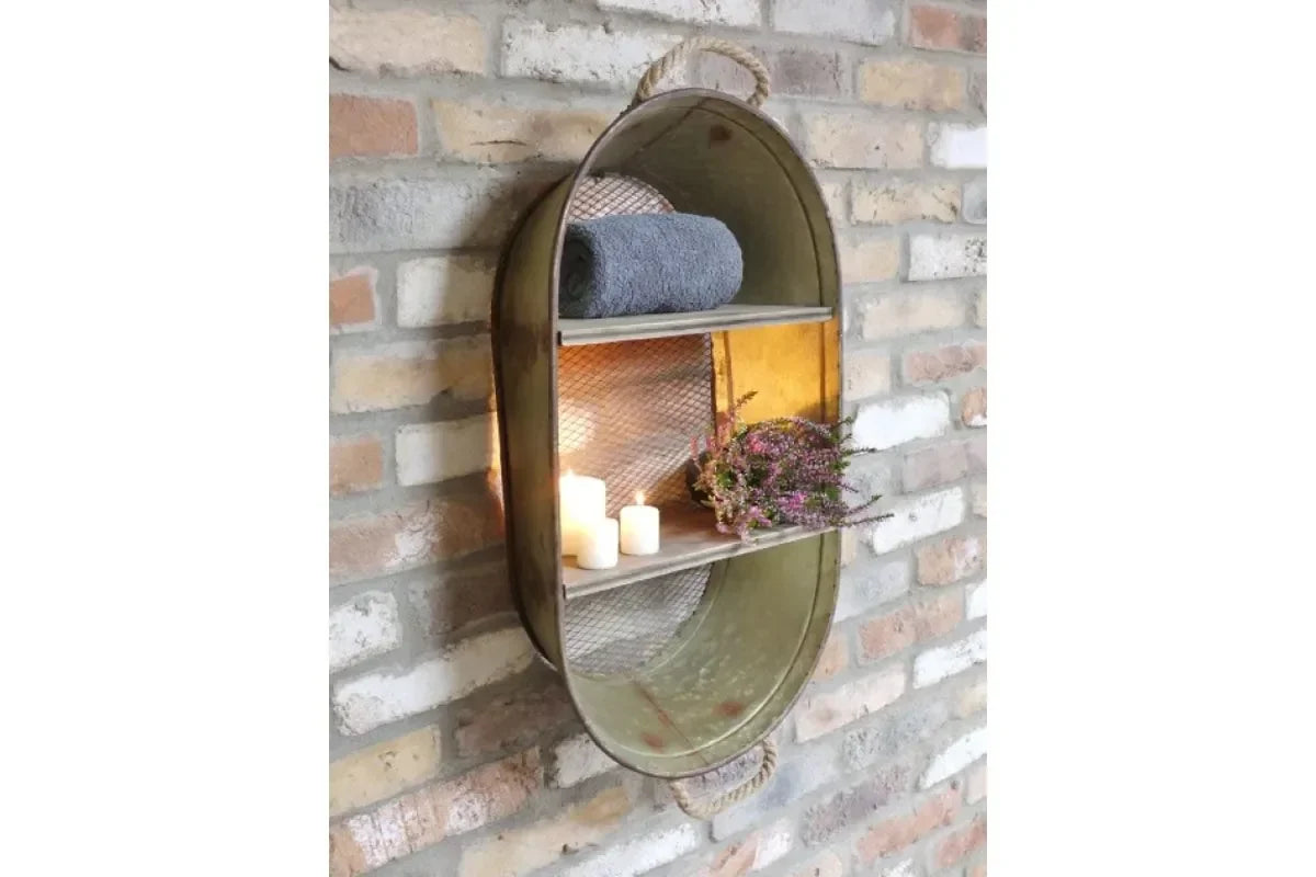 Oval metal wall shelf with rope handle, candles, rolled towel and flowers on brick backdrop