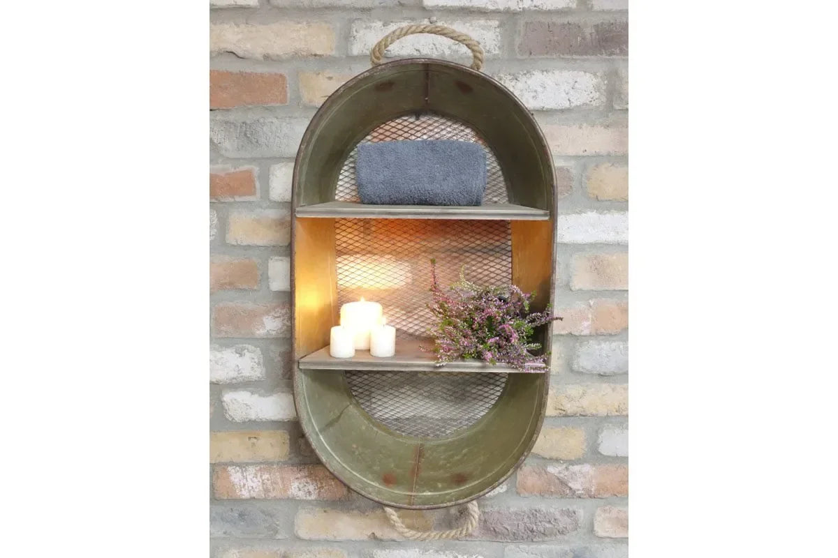 Oval metal wall shelf with mesh backing, candles, towel, and flowers on exposed brick wall