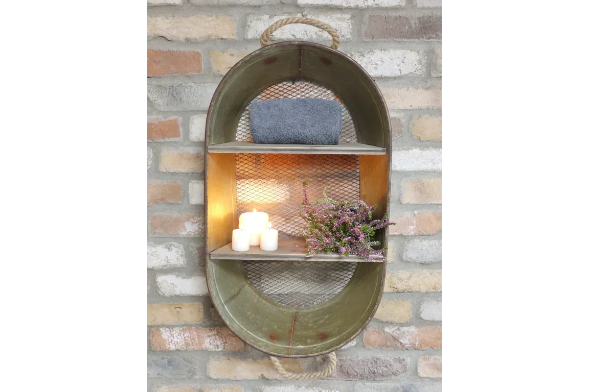 Oval metal wall shelf with mesh back, candles, towel, and flowers against brick wall
