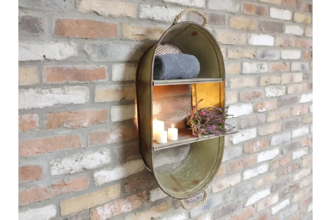 Metal wall shelf with mesh backing holding towel, candles, and flowers on brick wall