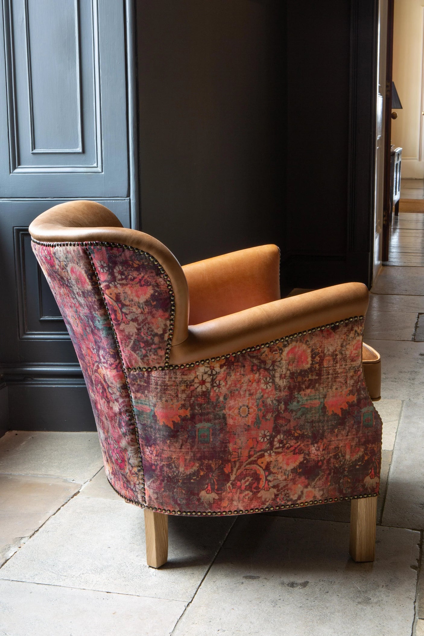 Patterned accent armchair with tan leather trim and wooden legs in a modern interior
