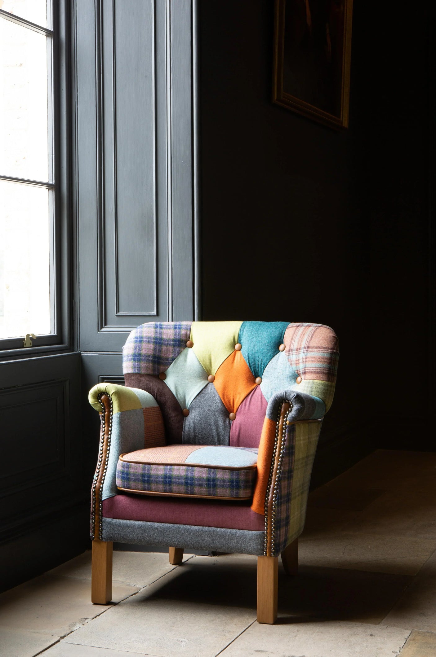 Patchwork accent armchair with wooden legs beside tall window on tiled floor