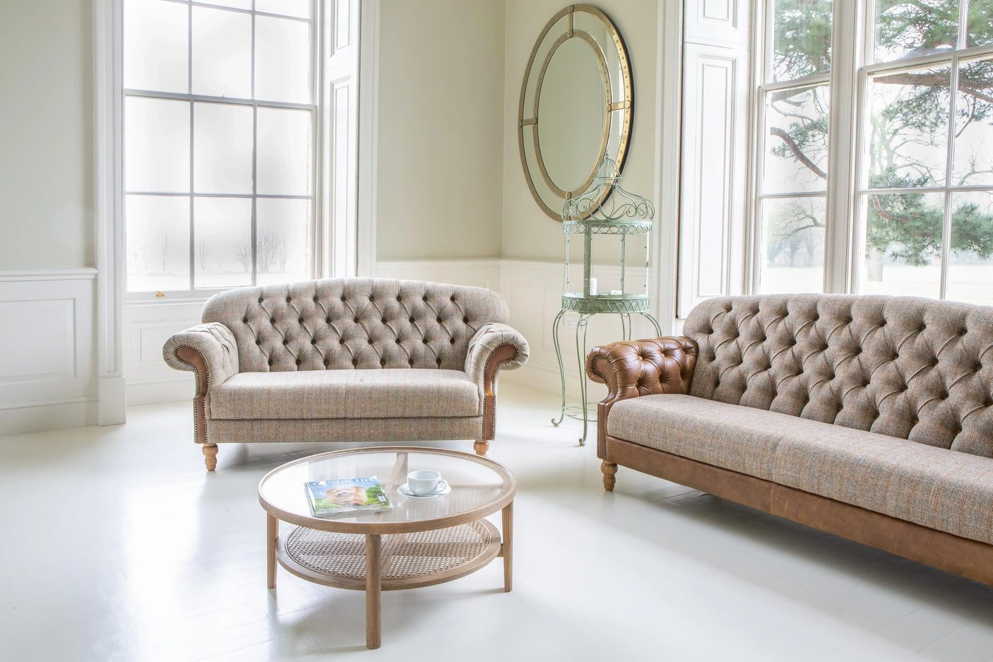 Tufted fabric and leather sofas with round wooden coffee table in bright living room