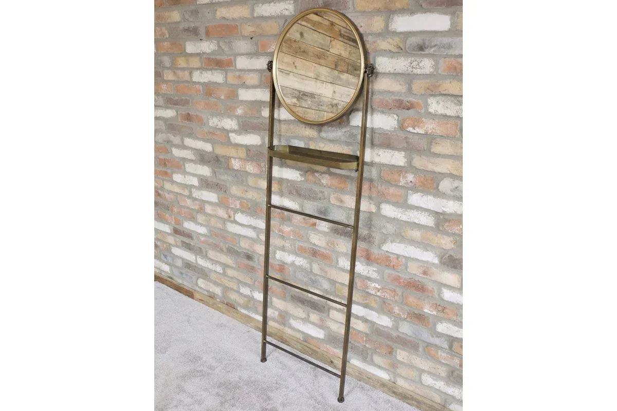 Metal ladder shelf with round mirror and wooden tray against exposed brick wall