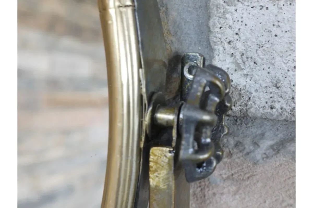 Close-up of brass wall mirror hanging bracket attached to stone wall