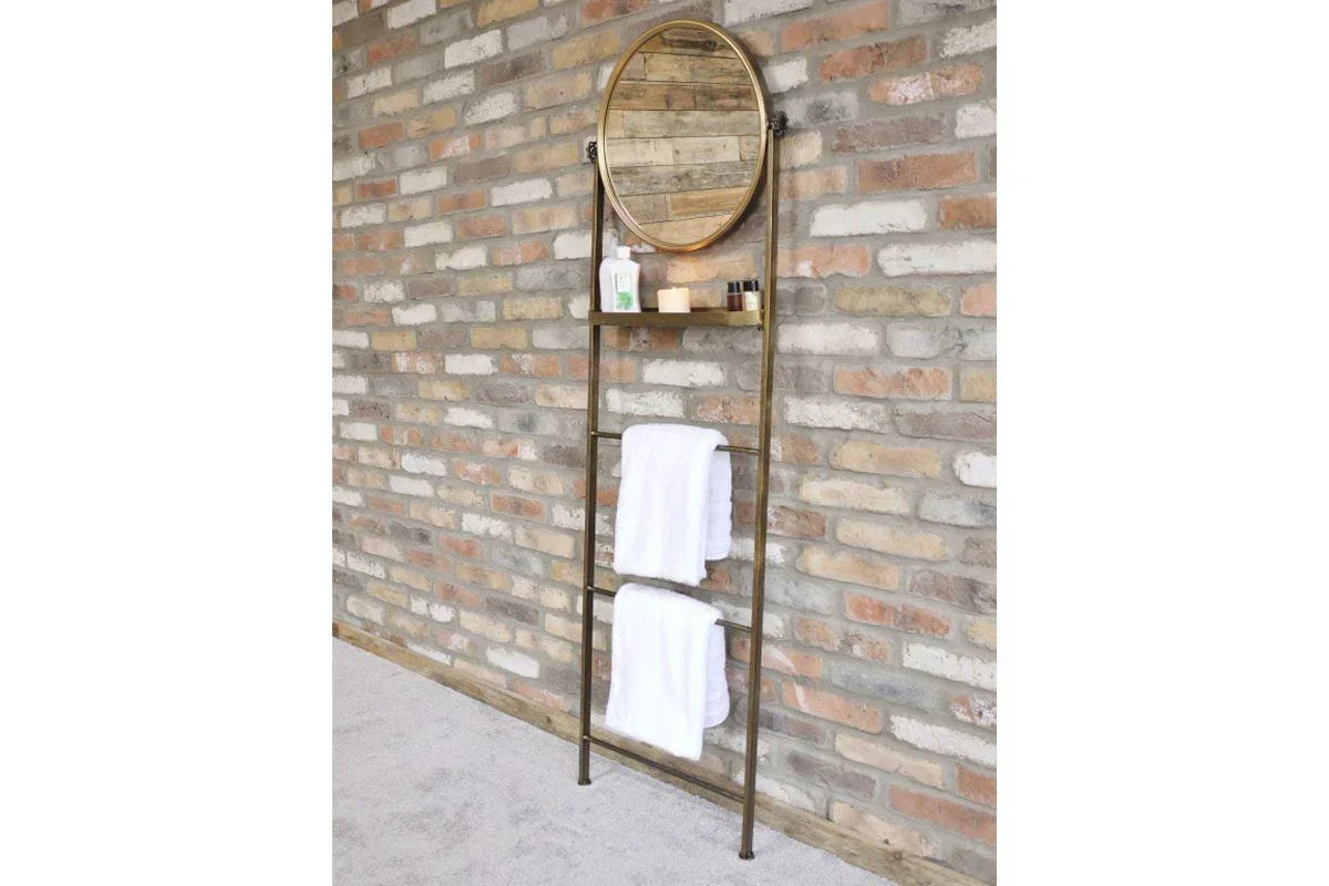 Ladder style towel rack with shelf and round mirror against exposed brick wall