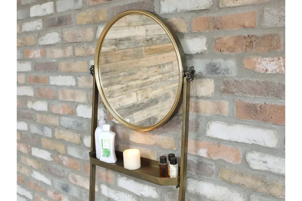 Round wall mirror with brass frame and built-in shelf holding toiletries and candle