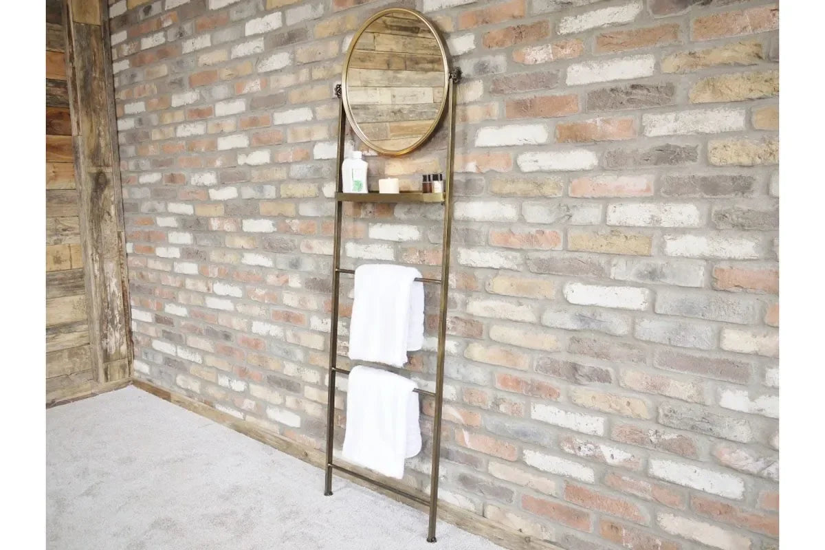 metal ladder shelf with round mirror and white towels against exposed brick wall