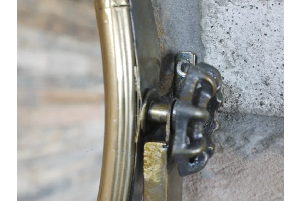 Close up of ornate gold mirror frame bracket with visible metal wall mount hardware