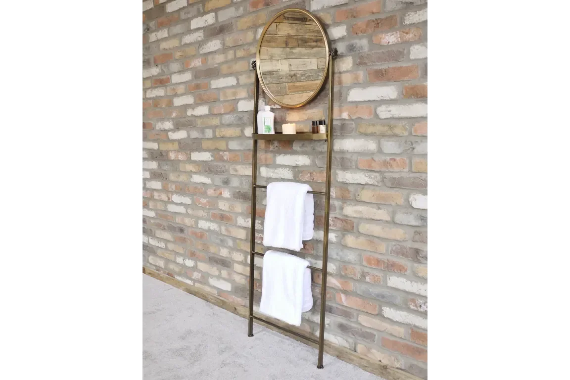 gold metal towel rack with round mirror and shelf on brick wall